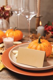 Beautiful autumn place setting with blank card and decor on wooden table