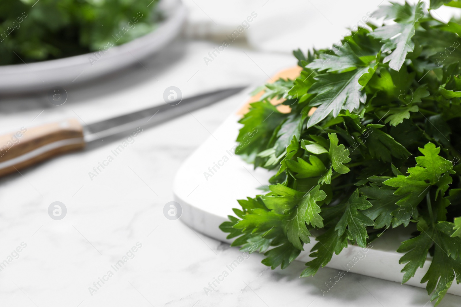 Photo of Bunch of fresh green parsley on white marble table, closeup. Space for text