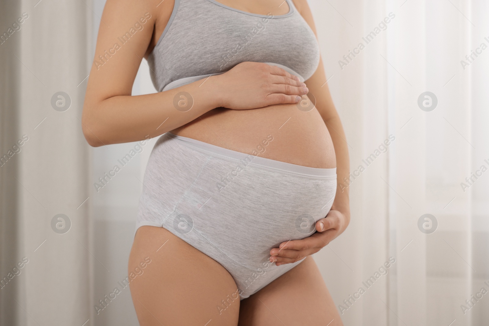 Photo of Pregnant woman in comfortable maternity underwear indoors, closeup