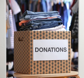 Photo of Donation box with clothes on table indoors