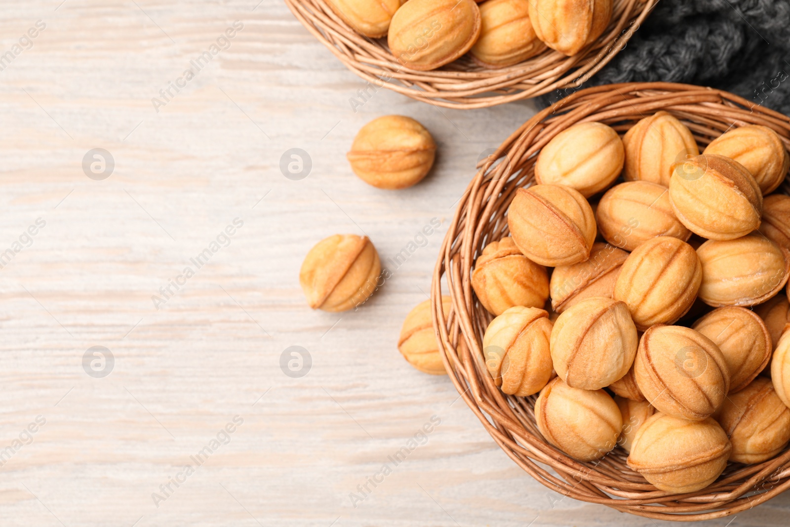 Photo of Bowls of delicious nut shaped cookies on white wooden table, flat lay. Space for text