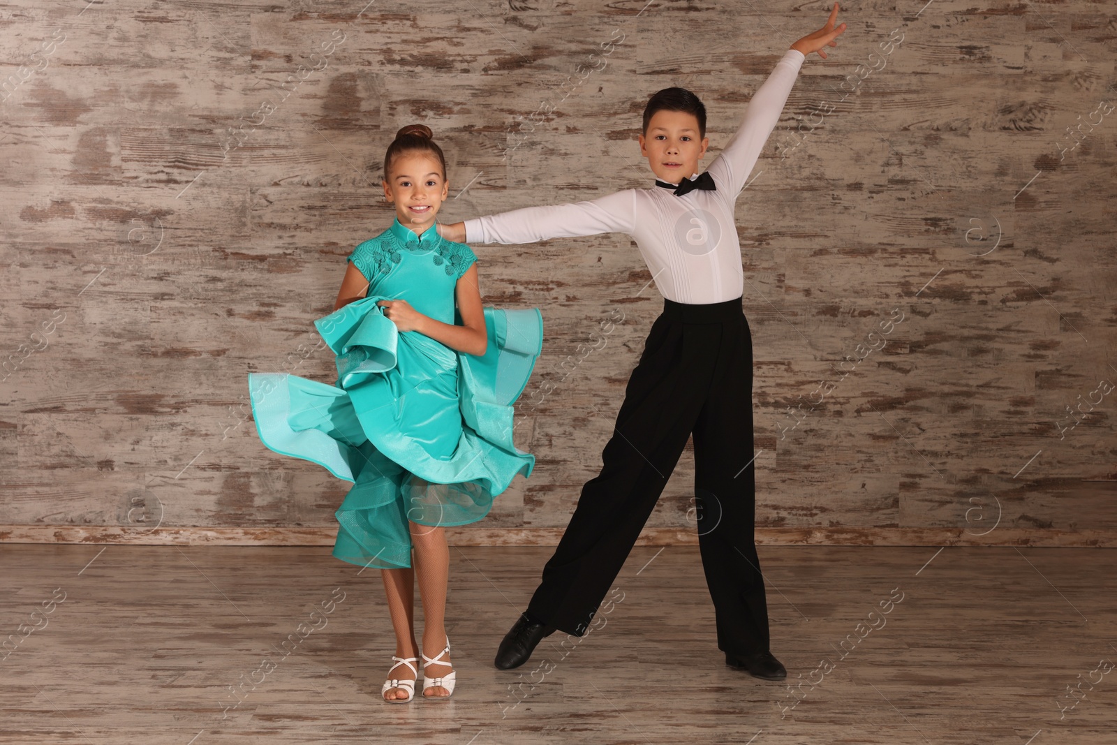 Photo of Beautifully dressed couple of kids dancing together in studio