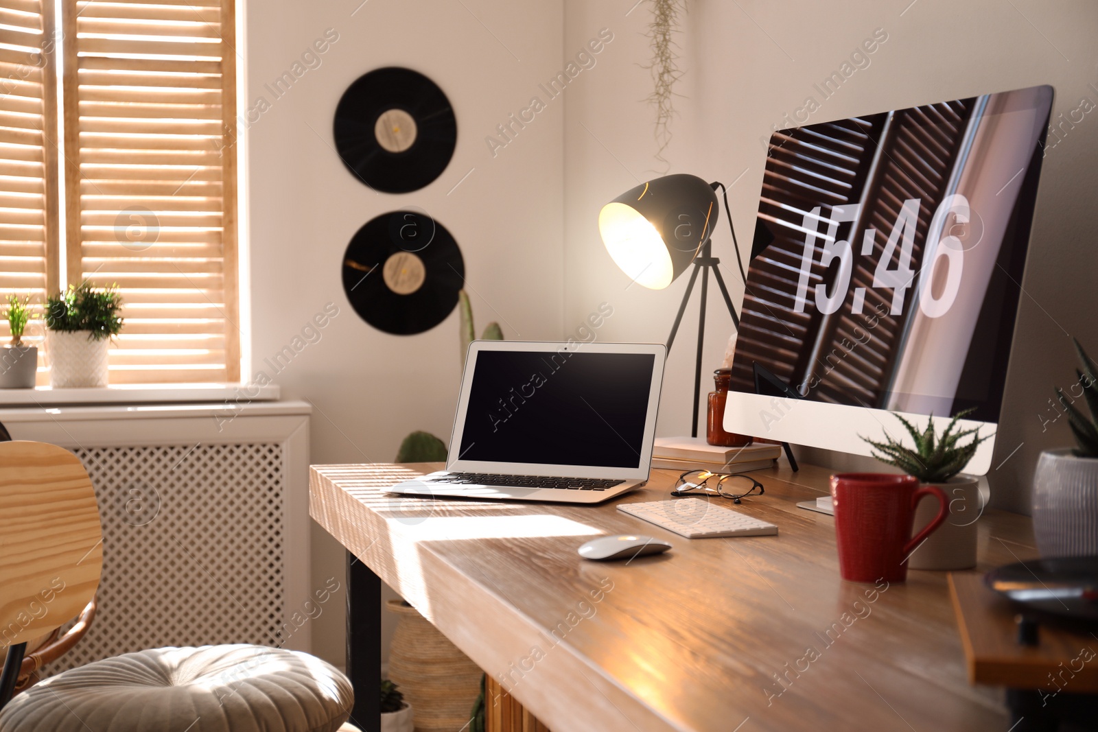 Photo of Modern computer and laptop on wooden desk in room. Interior design