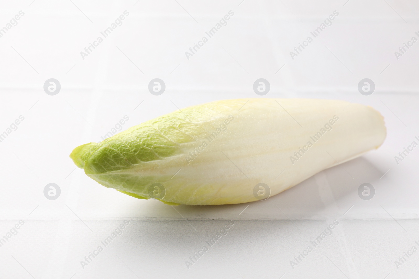 Photo of Fresh raw Belgian endive (chicory) on white tiled table