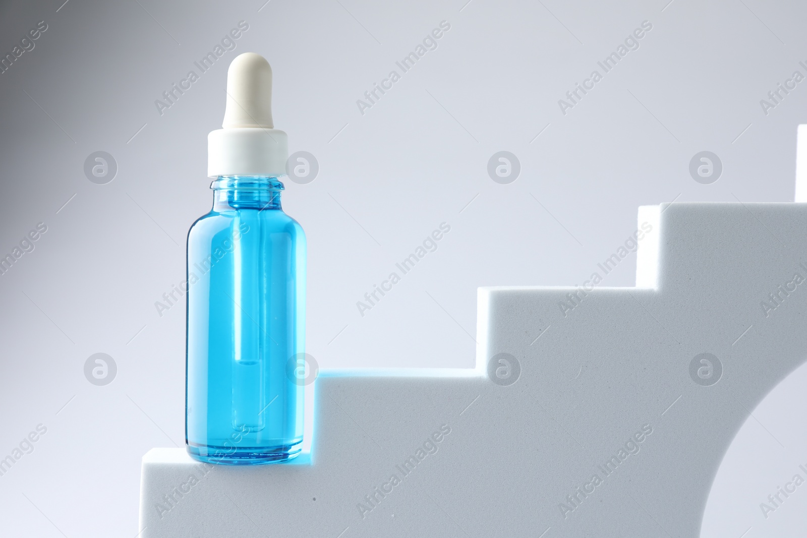 Photo of Bottle of luxury serum on stairs against white background