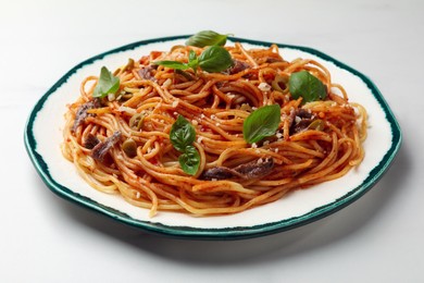 Photo of Delicious pasta with anchovies, tomato sauce and basil on white table