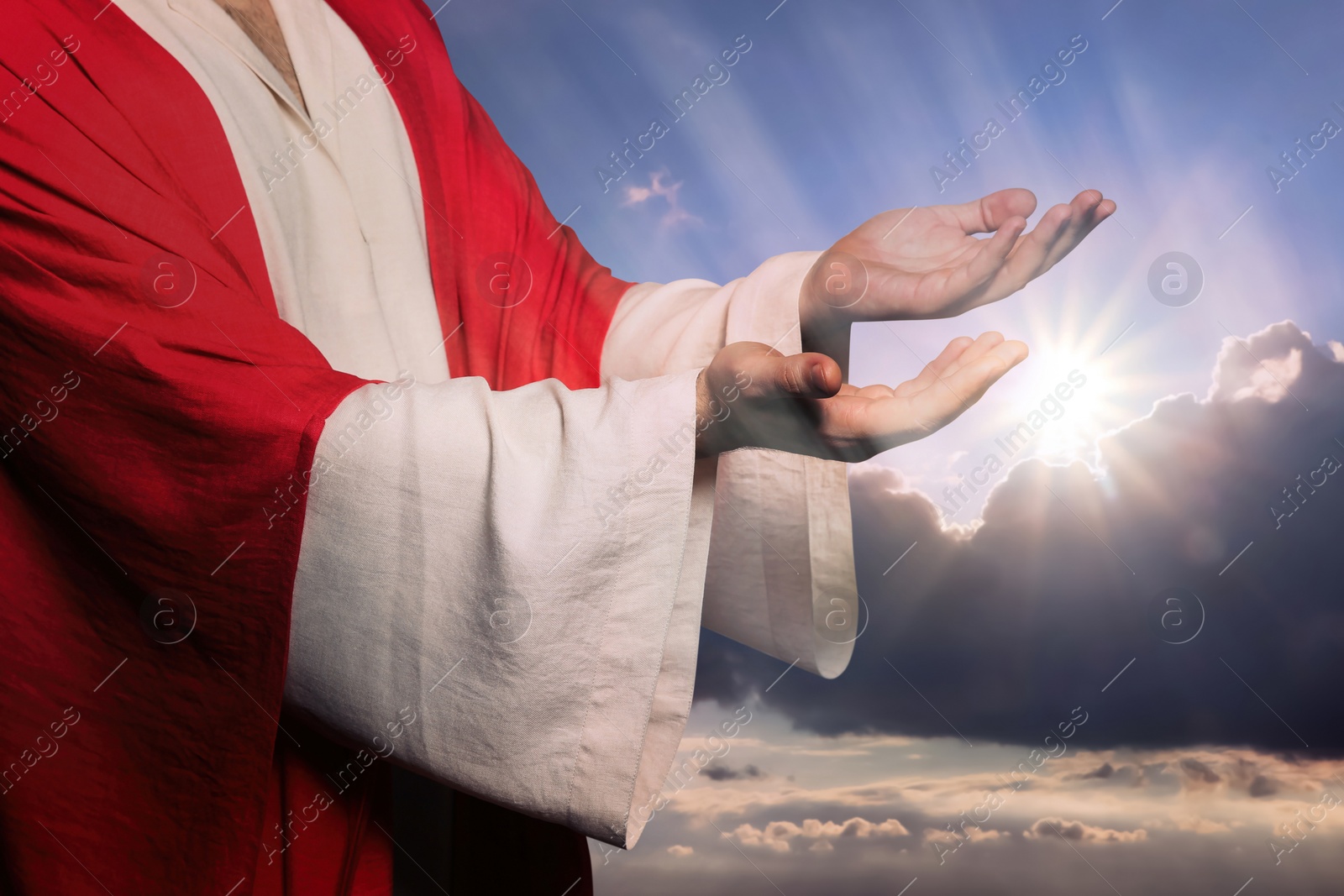 Image of Jesus Christ reaching out his hands and praying against blue sky 