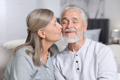 Senior woman kissing her beloved man at home