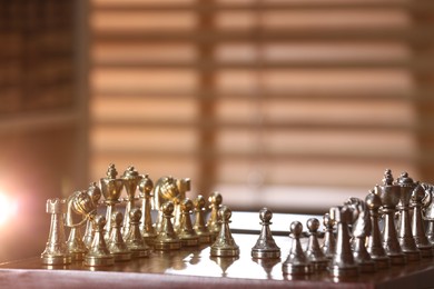 Chessboard with game pieces near window indoors, space for text