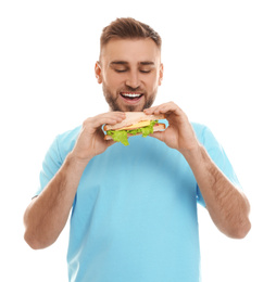 Young man eating tasty sandwich on white background