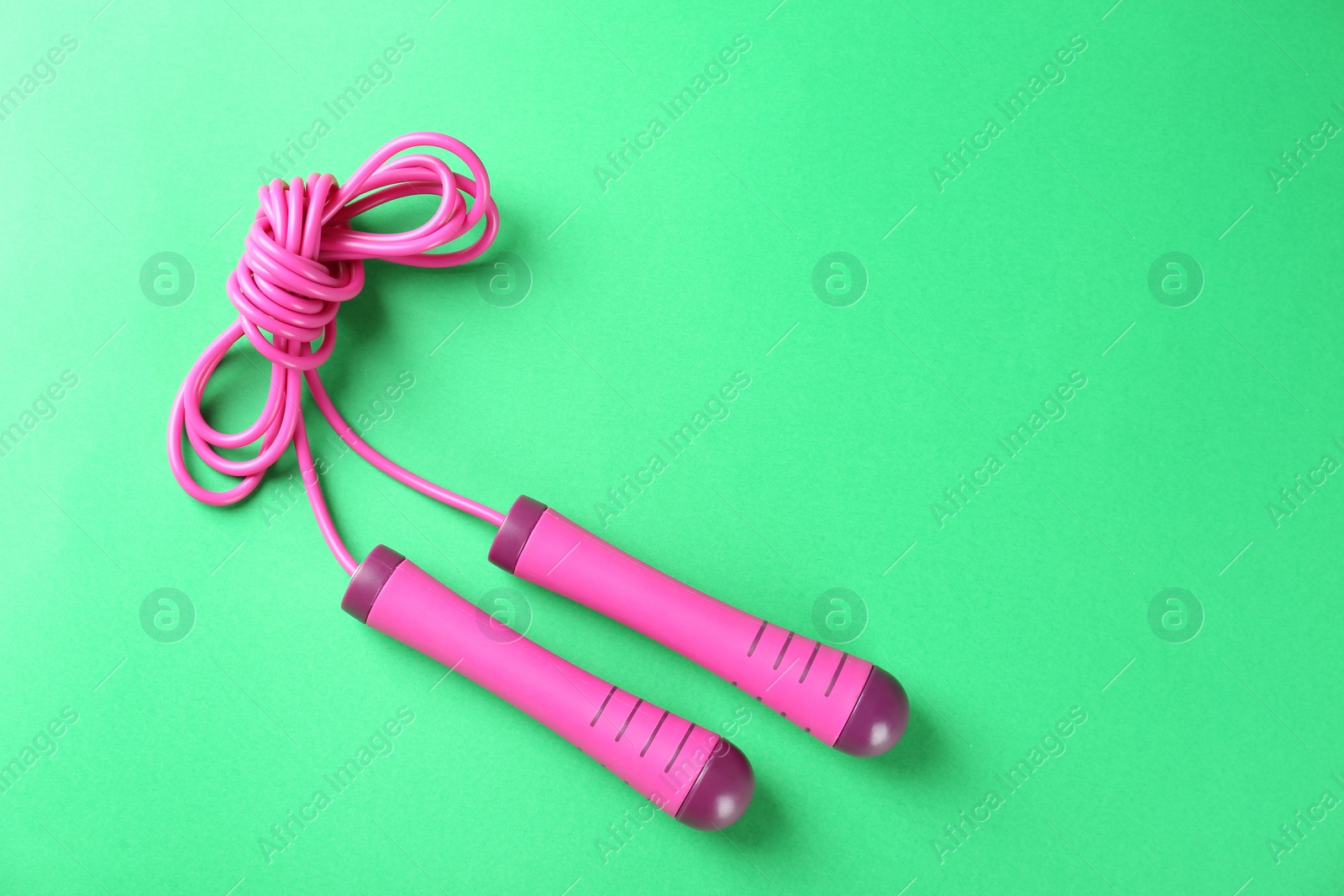 Photo of Skipping rope on green background, top view. Space for text