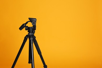 Modern tripod on yellow background. Space for text