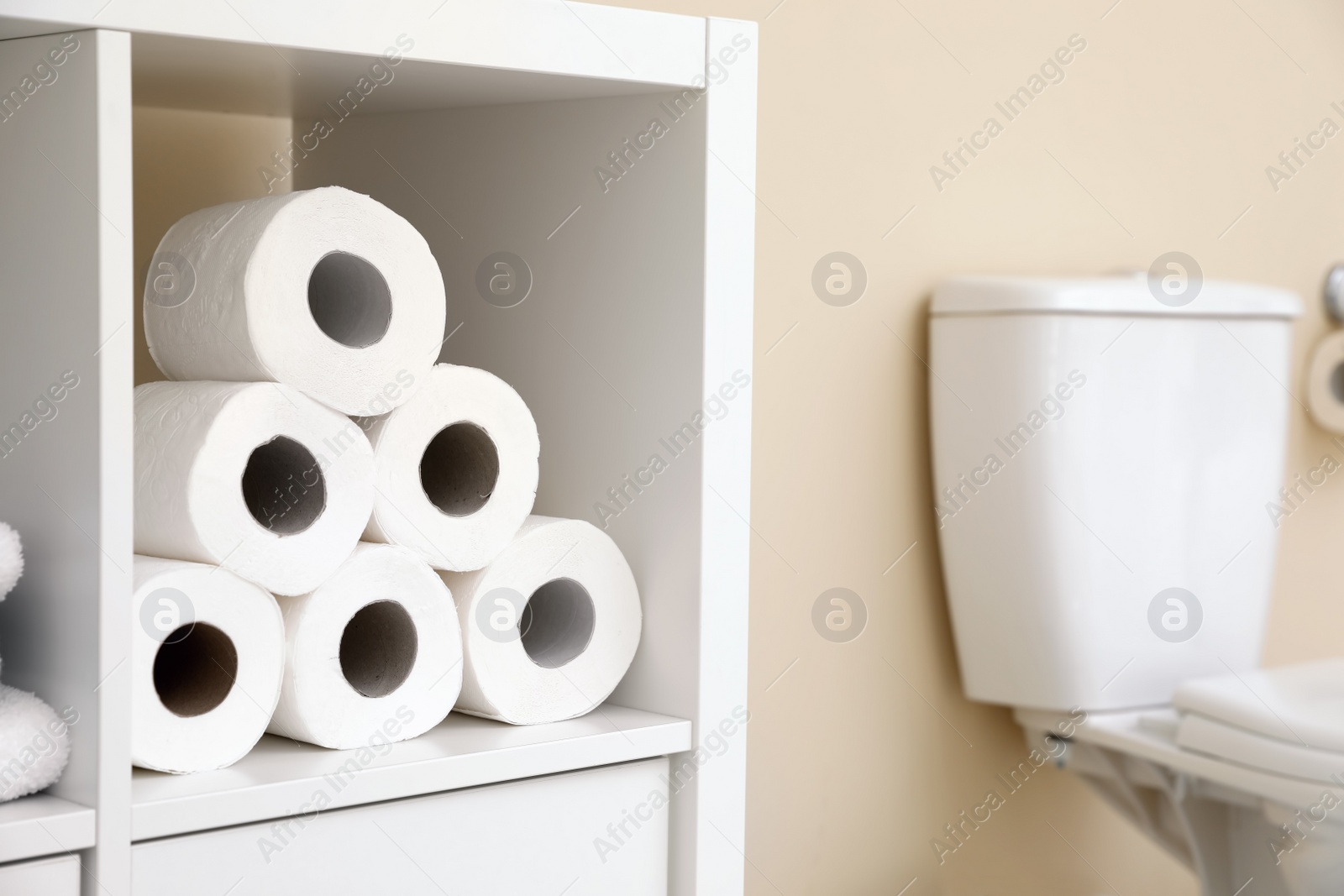 Photo of Toilet paper rolls on cabinet shelf in bathroom