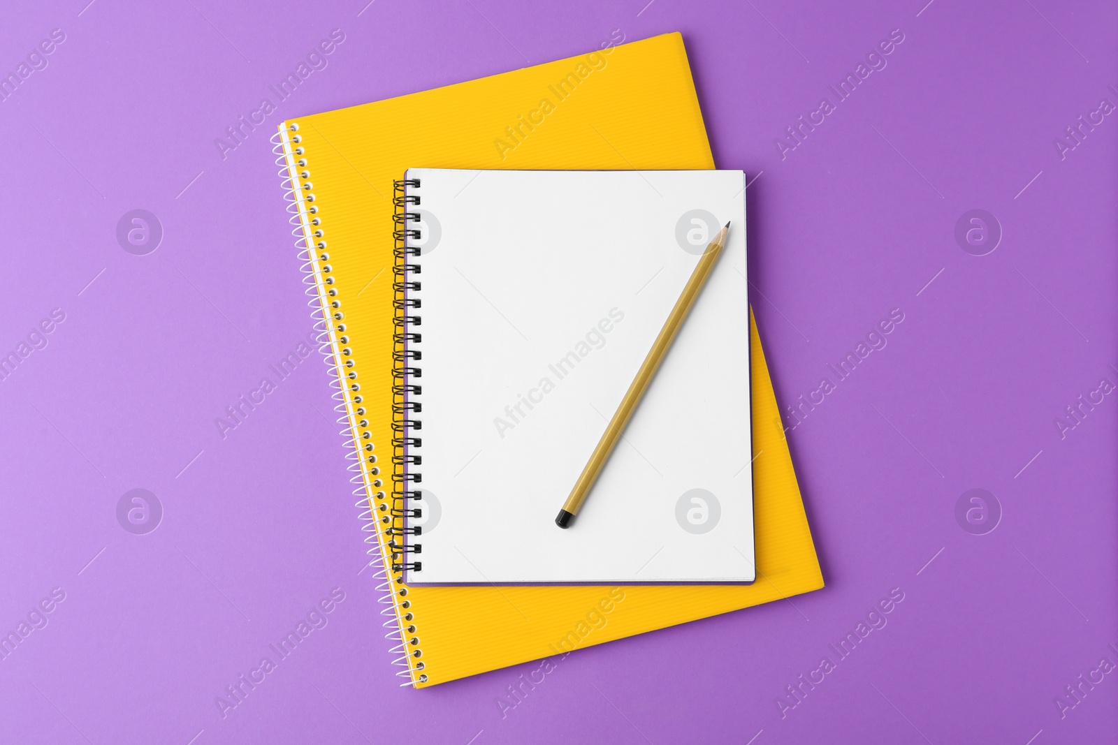 Photo of Notebooks with pencil on purple background, top view