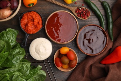 Different marinades and products on wooden table, flat lay