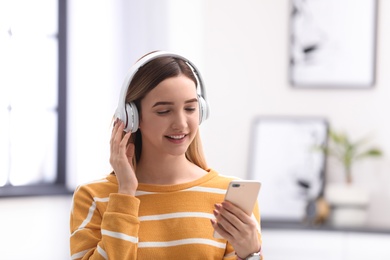 Photo of Teenage girl listening to music with headphones against blurred background