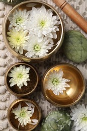 Tibetan singing bowls with beautiful chrysanthemum flowers, mallet and stones on table, flat lay