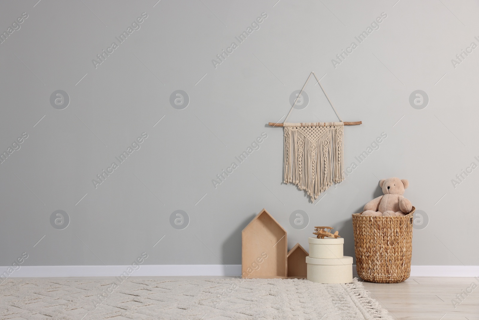 Photo of Beautiful children's room with grey wall, decor elements and toys, space for text. Interior design