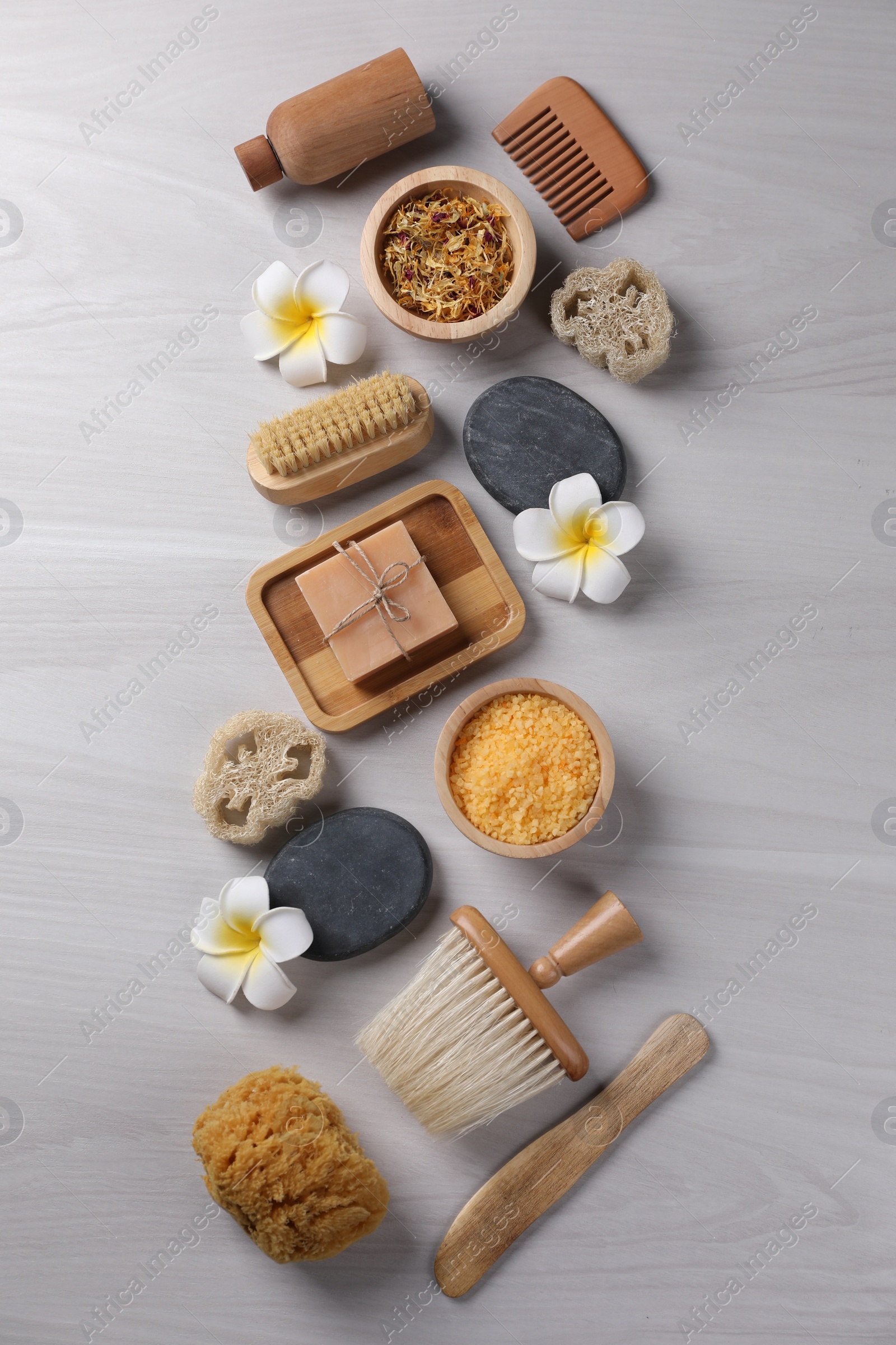 Photo of Flat lay composition with different spa products and flowers on light wooden table