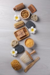 Flat lay composition with different spa products and flowers on light wooden table