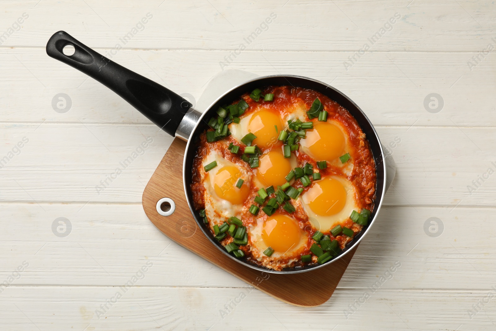 Photo of Delicious shakshuka in frying pan on white wooden table, top view