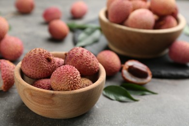 Fresh ripe lychee fruits in bowl on grey table. Space for text