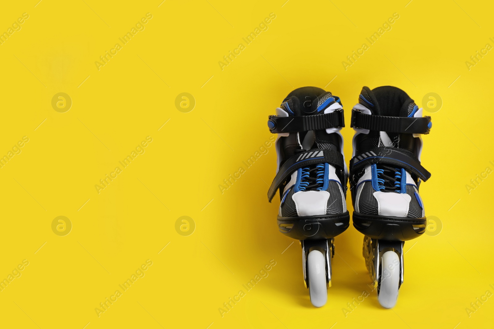 Photo of Pair of inline roller skates on color background. Space for text