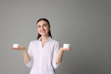 Photo of Cosmetologist with cosmetic products on grey background, space for text