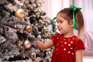 Photo of Cute little child near Christmas tree at home