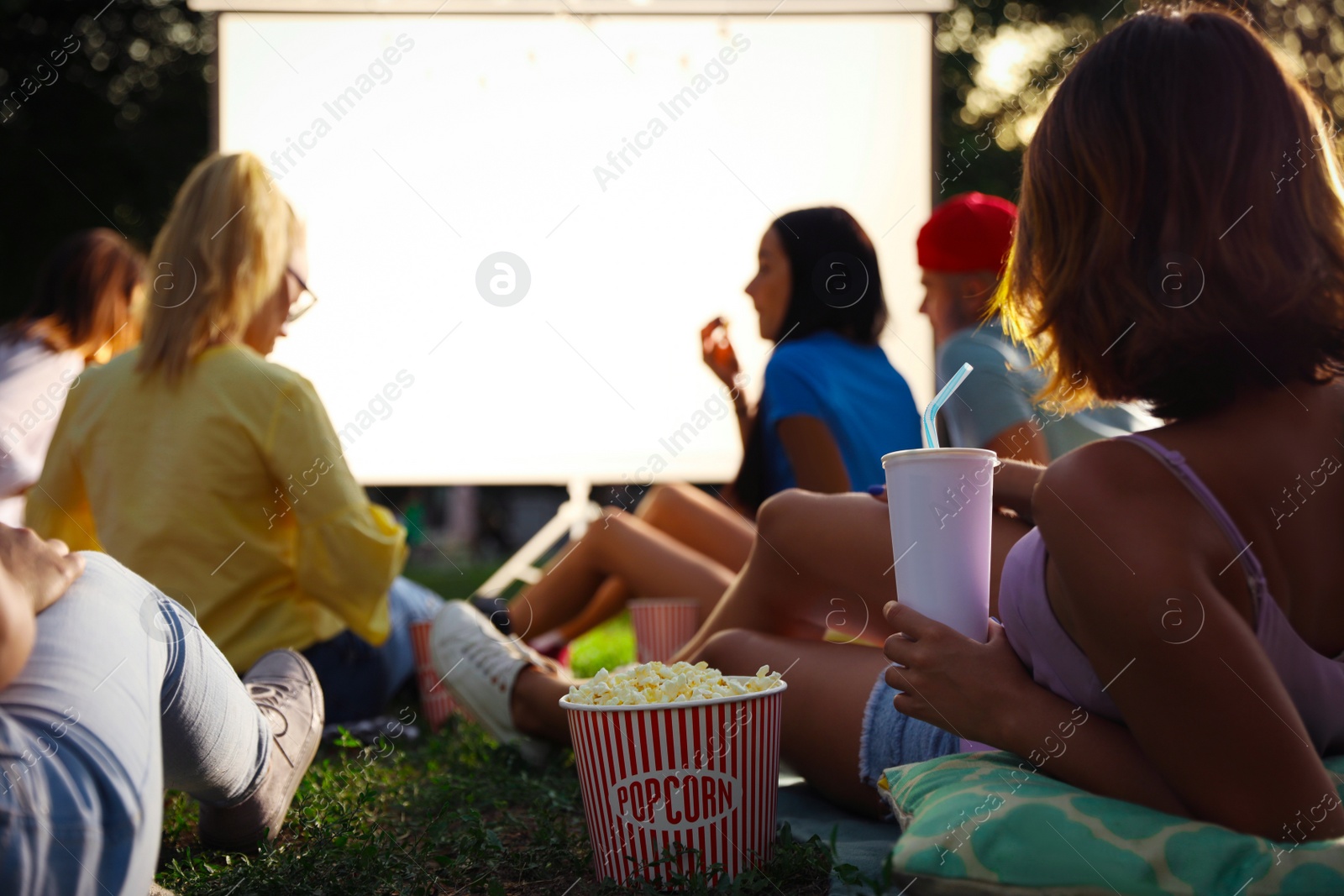 Photo of Young people with popcorn watching movie in open air cinema. Space for text