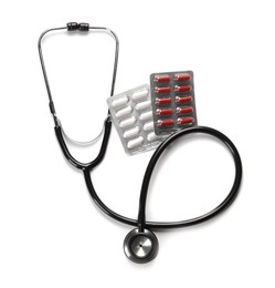 Stethoscope and pills on white background, top view