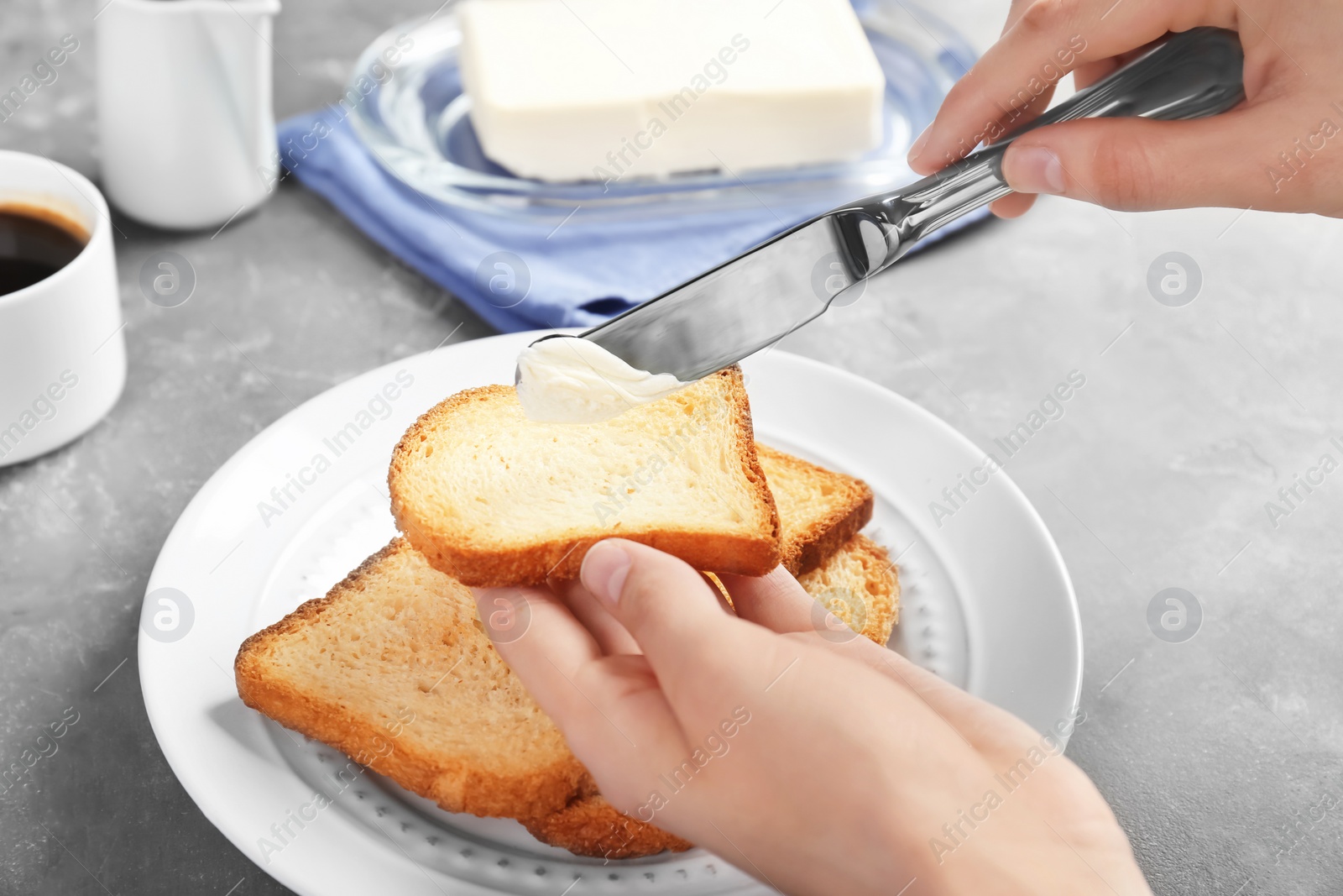 Photo of Woman spreading butter on toasted bread at table, closeup