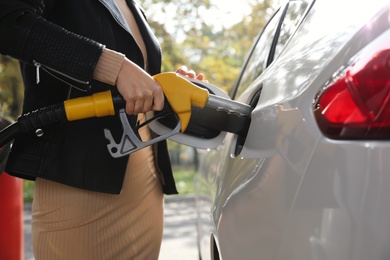 Photo of Woman refueling car at self service gas station, closeup