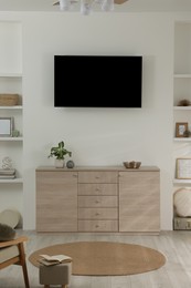 Stylish TV set mounted on wall in room