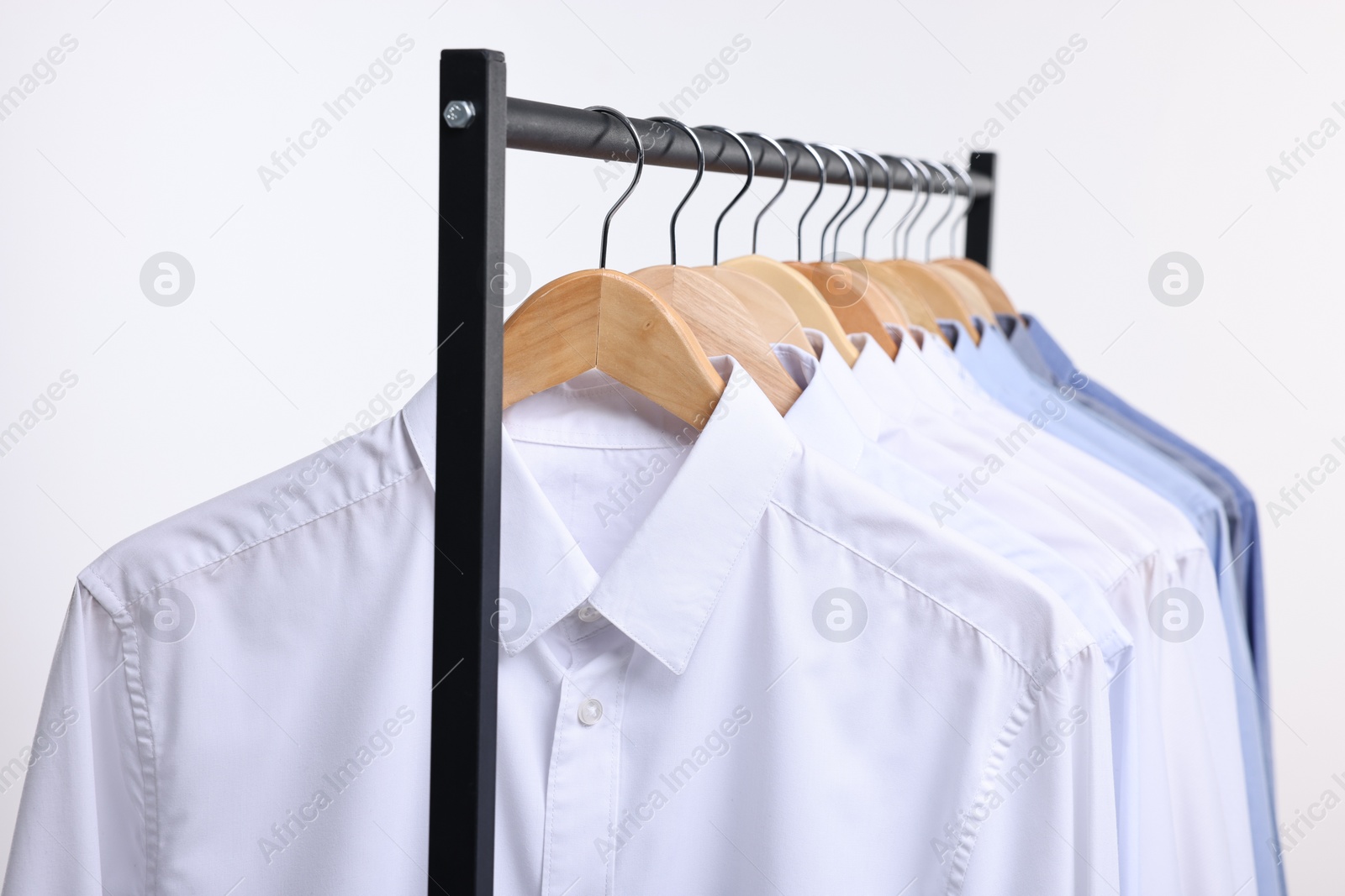 Photo of Dry-cleaning service. Many different clothes hanging on rack against white background, closeup