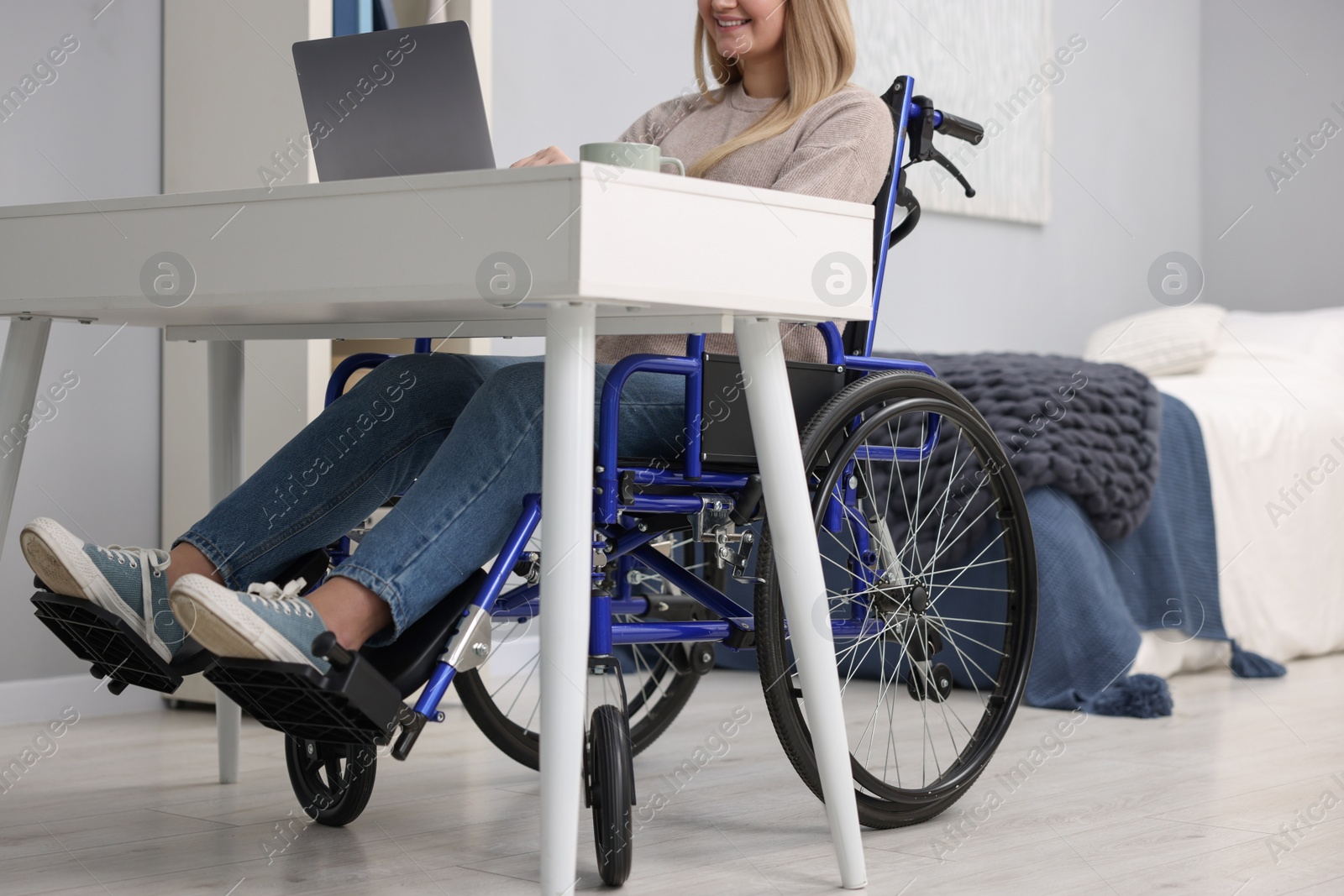 Photo of Woman in wheelchair using laptop at home, closeup