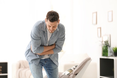 Photo of Young man suffering from stomach ache at home