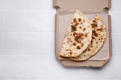 Photo of Tasty pizza calzones on white tiled table, top view. Space for text