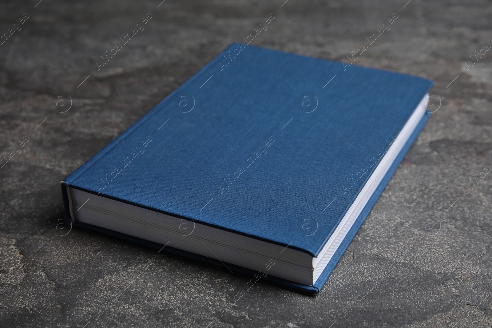 Photo of Hardcover book on grey stone table. Space for text