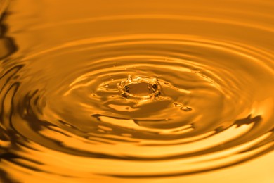 Image of Splash of golden oily liquid with drops as background, closeup