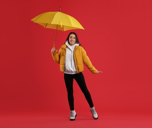Photo of Woman with umbrella caught in gust of wind on red background