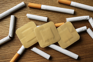 Photo of Nicotine patches and cigarettes on wooden table, flat lay