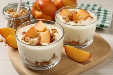 Photo of Delicious yogurt with fresh peach on granola wooden table, closeup