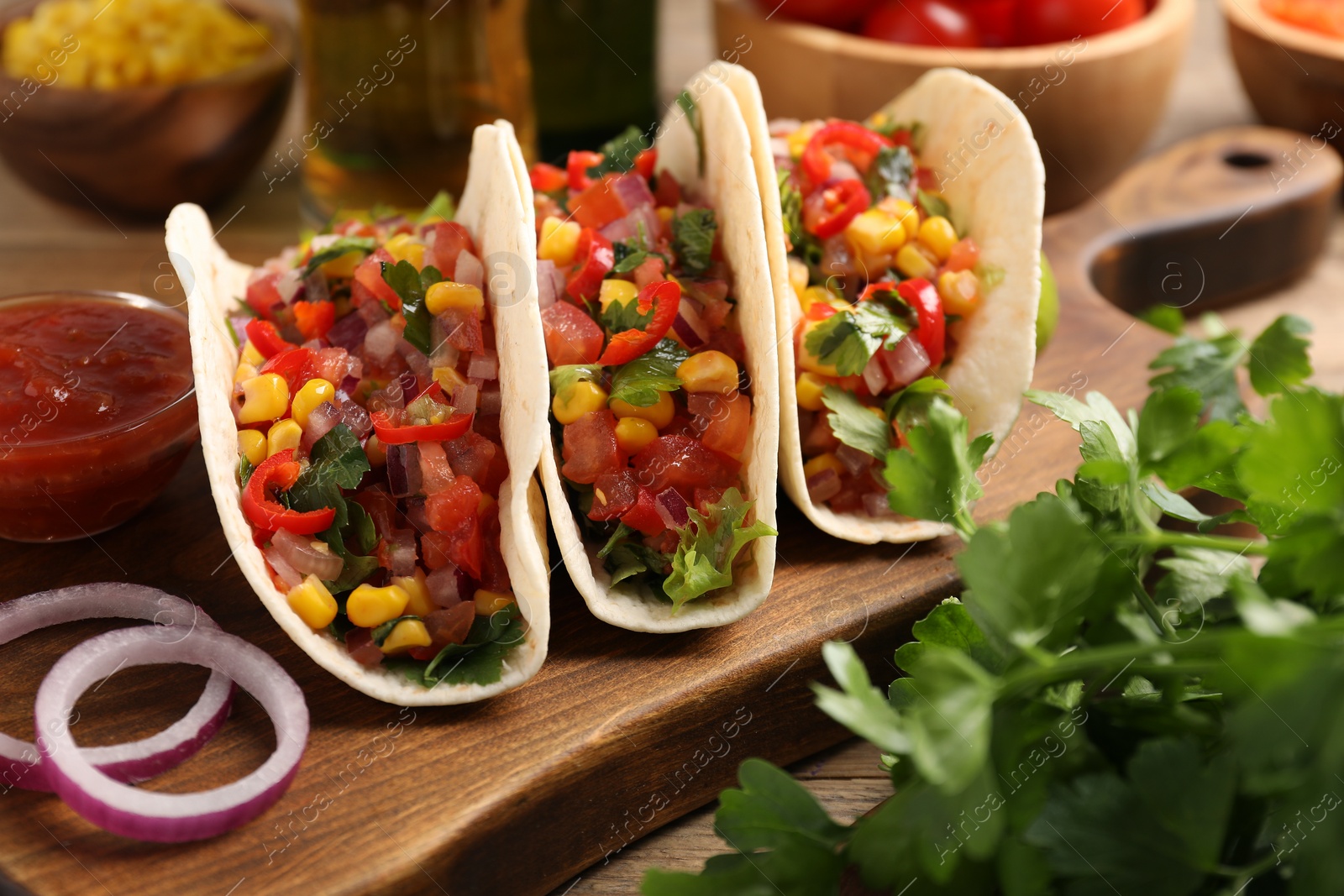 Photo of Tasty tacos with vegetables on wooden table, closeup