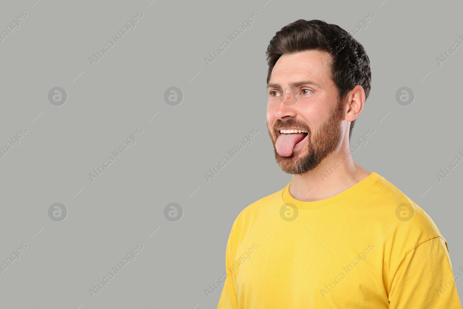 Photo of Man showing his tongue on gray background, space for text