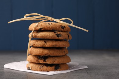 Photo of Stack of delicious chocolate chip cookies on grey table. Space for text