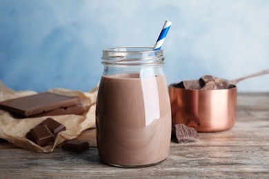 Photo of Jar with tasty chocolate milk on wooden table. Dairy drink