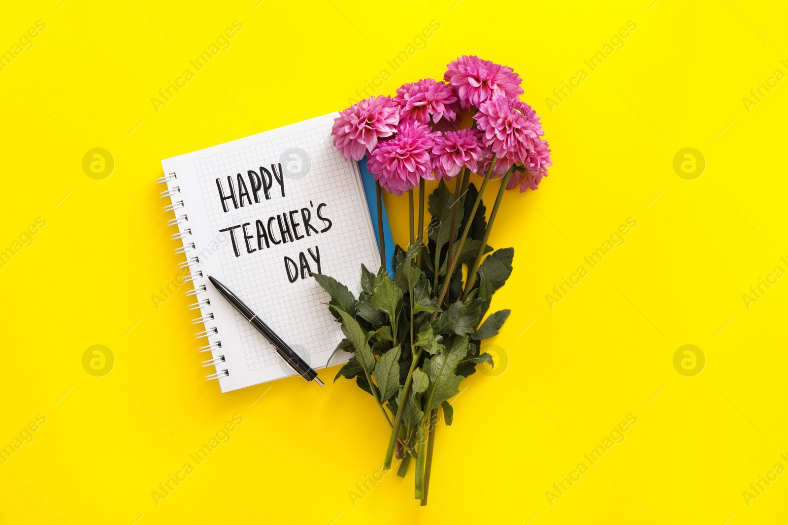 Photo of Beautiful flowers and notebook with words HAPPY TEACHER'S DAY on yellow background, flat lay