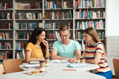 Young people discussing group project at table in library