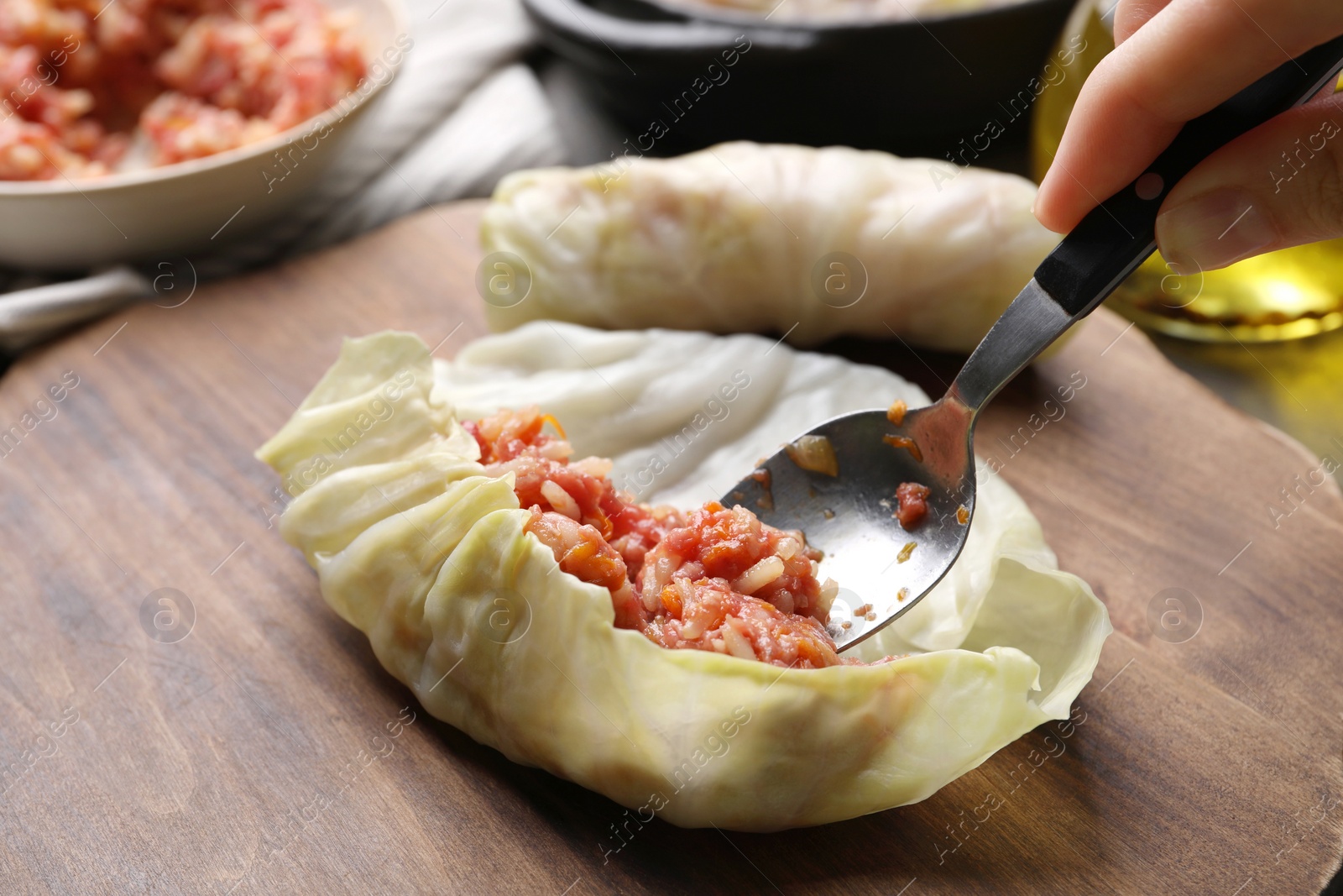 Photo of Woman preparing stuffed cabbage roll, closeup view